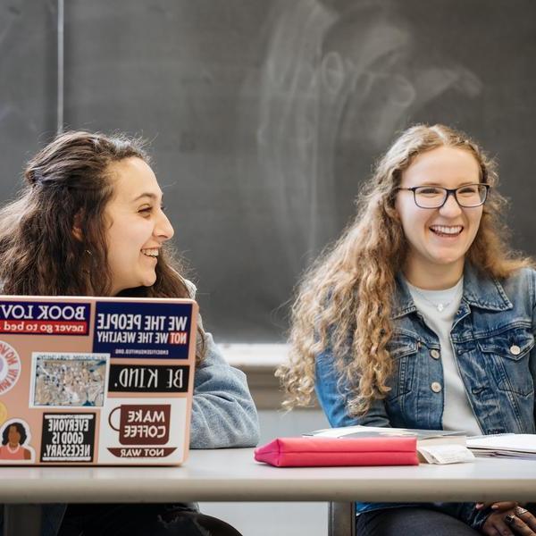 Two math major students smile and laugh as they attend class.